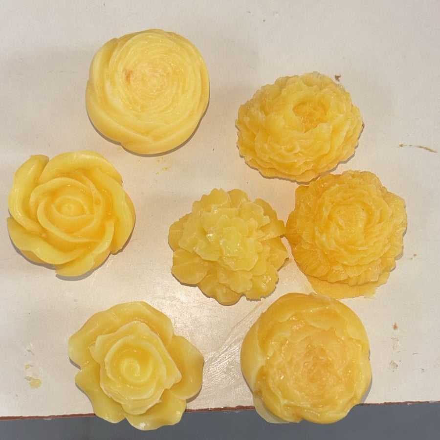 Sunrise yellow handcrafted soap roses, set of seven, on a cream surface